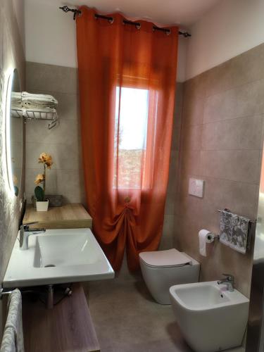 an orange shower curtain in a bathroom with a toilet and sink at Rosanna House in Bombarde Beach in Alghero