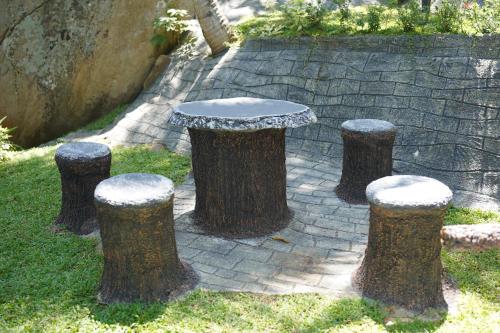 a table and four stump stools in the grass at Rock Garden Villa Pinnawala in Rambukkana