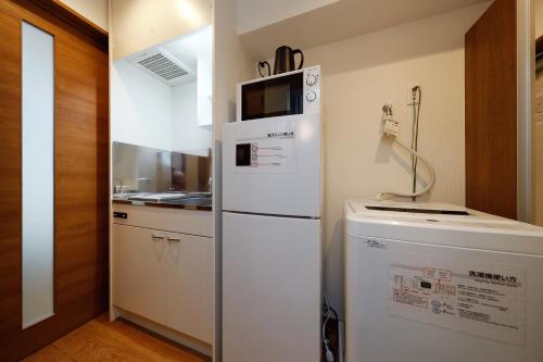a kitchen with a refrigerator with a microwave on top at Zenith Garden TOGOSHI in Tokyo