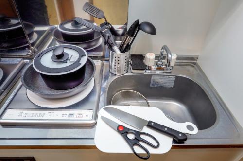 a kitchen sink with scissors and a cup in it at Zenith Garden TOGOSHI in Tokyo