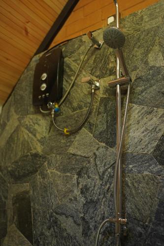 a shower with a microphone on a stone wall at Rock Garden Villa Pinnawala in Rambukkana