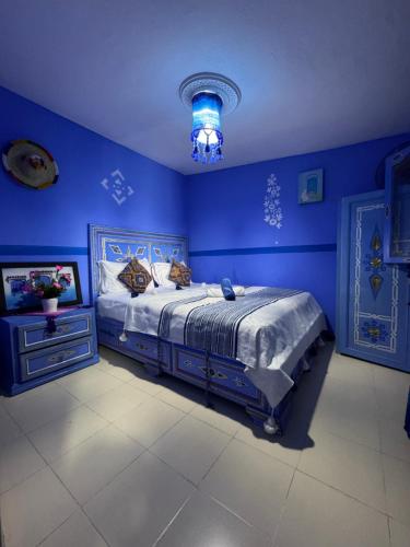 a blue bedroom with a bed and a blue wall at DAR AMRANi in Chefchaouene