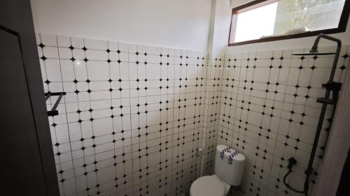 a white tiled bathroom with a toilet and a window at Ntala in Komodo Labuan Bajo Airport