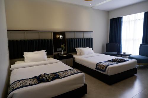 a hotel room with two beds and a chair at D'more Kuakata Hotel & Resort in Kuākāta