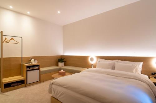 a bedroom with a large white bed and a table at Goyang Hotel Yuji in Goyang