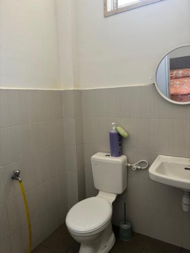 a bathroom with a toilet and a sink and a mirror at KM Homestay in Merlimau