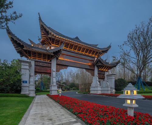 a large pagoda over a road with red flowers at Song Hotel Chengdu Qingcheng in Dujiangyan