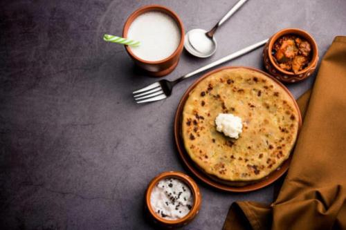 a table with a plate of food and a drink at Hotel The Rasa at Vasundhara in Ghaziabad