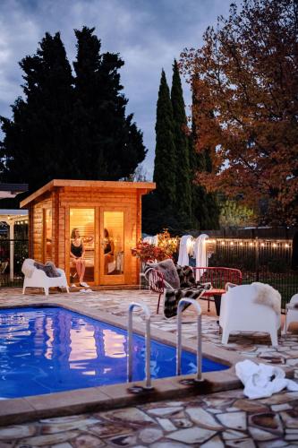 a woman standing next to a tiny house next to a pool at The Oriana Orange - Retro Hotel & Resort in Orange