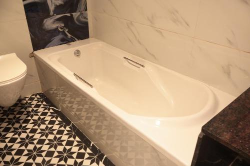 a white bath tub in a bathroom with a toilet at Hotel Sapphire Inn Residency in Thane