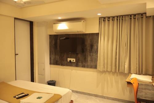 a room with a bed and a tv and a table at Hotel Sapphire Inn Residency in Thane