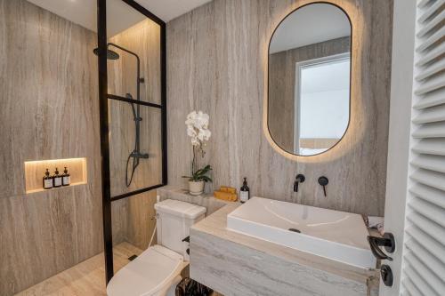 a bathroom with a sink and a toilet and a mirror at Cemagi Suites Brand New 3BR Villas in Cemagi