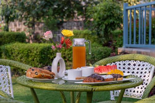 een tafel met een bord eten en een kan sap bij Corbett Calling with Projector Set-Up by StayVista in Rāmnagar