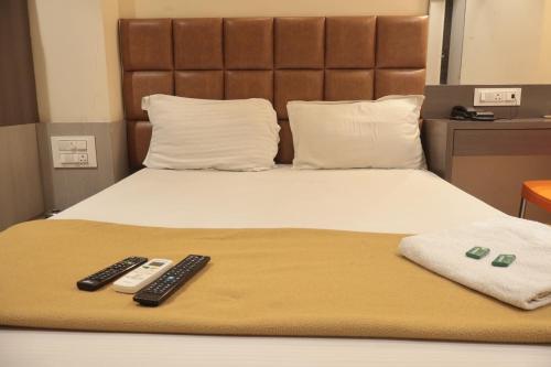 a bed with two remote controls sitting on it at Hotel Sapphire Inn Residency in Thane