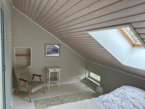 a bedroom with a sloped ceiling with a window at Wooden house in Käpylä in Helsinki