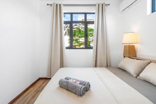 a bedroom with a large white bed with a window at Villa Olive avec piscine privée, proche de la mer in Flic-en-Flac