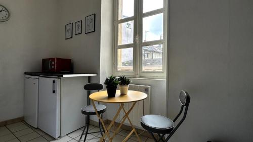 une petite table et des chaises dans une cuisine avec une fenêtre dans l'établissement Bel appartement proche gare, à Nevers
