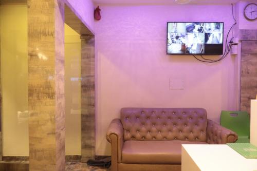 a room with a couch and a tv on a wall at Hotel Sapphire Inn Residency in Thane