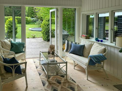 a porch with a couch and chairs and a glass table at Spacious Holiday Home In Peaceful North Zealand in Melby