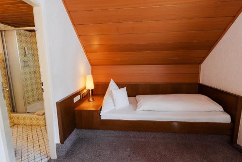 a small bedroom with a bed and a bathroom at Landgasthof zur Linde in Heimbuchenthal