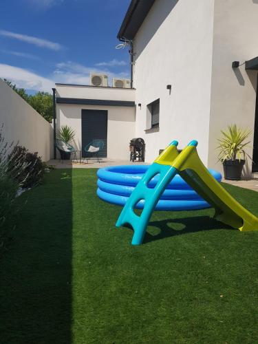 une aire de jeux avec des toboggans bleus et jaunes dans une cour dans l'établissement Villa avec Piscine pour un séjour d'exception !, à Calvisson