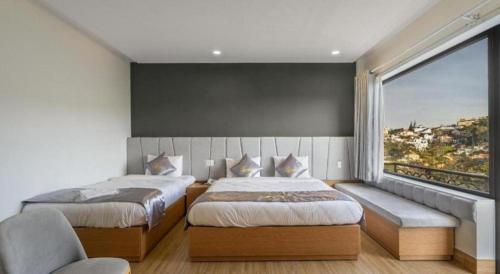 a bedroom with two beds and a large window at Gold View Boutique Hotel Đà Lạt in Da Lat