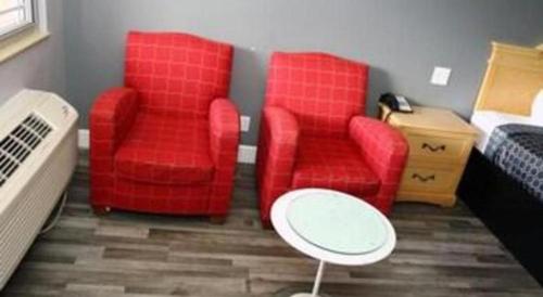 a room with two red chairs and a bed at Grand Park Inn in Baldwin Park