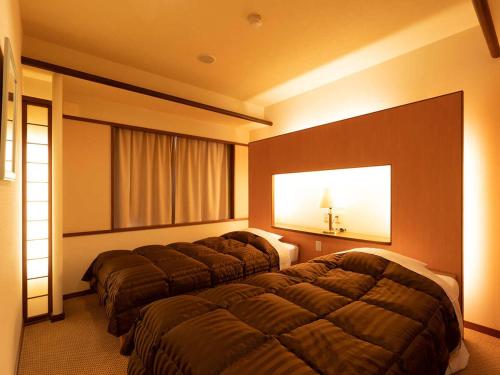 a hotel room with two beds and a window at Ooedo Onsen Monogatari Higashiyama Grand Hotel in Aizuwakamatsu