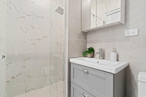 a white bathroom with a sink and a shower at Stylish 2 Bedroom Unit Close to CBD in Evandale