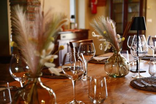 a wooden table with wine glasses and vases with flowers at Agriturismo Cascina Cipressa in San Romano
