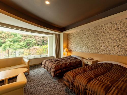 a hotel room with two beds and a window at Ooedo Onsen Monogatari Higashiyama Grand Hotel in Aizuwakamatsu