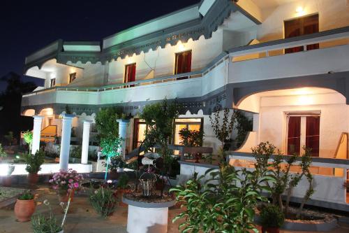 a large white building with potted plants in front of it at Hotel Dimitra Sun in Archangelos