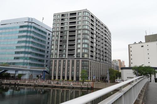 a tall building next to a river with a bridge at Rembrandt Style Yokohama Sakuragicho in Yokohama