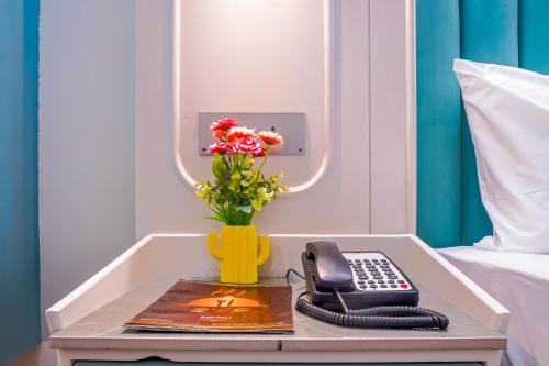 a table with a phone and a vase with flowers at Hotel Horizon By Shanti in New Delhi