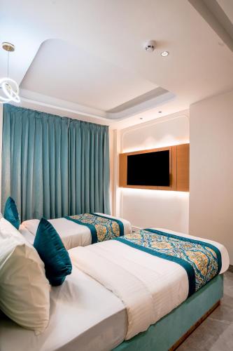 two beds in a hotel room with blue curtains at Hotel Horizon By Shanti in New Delhi