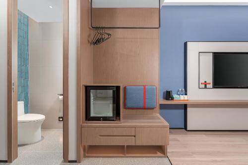 a bathroom with a tv on a wooden cabinet at Holiday Inn Express Kunming Economic Dev Zone by IHG in Kunming