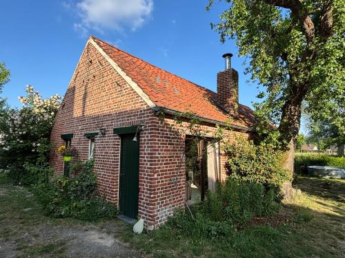 an old brick house with a green door at Bakhuisje Peer in Peer