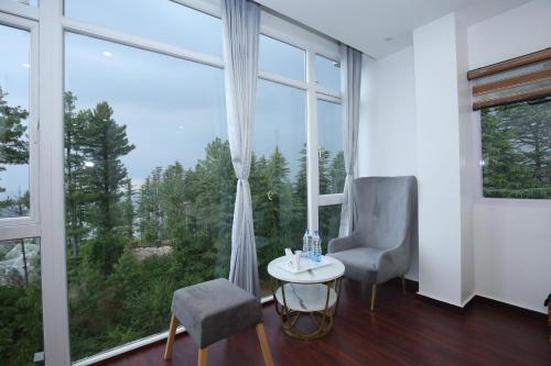 a room with two chairs and a table and large windows at The Snow Castle Kufri - A hidden gem in KUFRI in Shimla