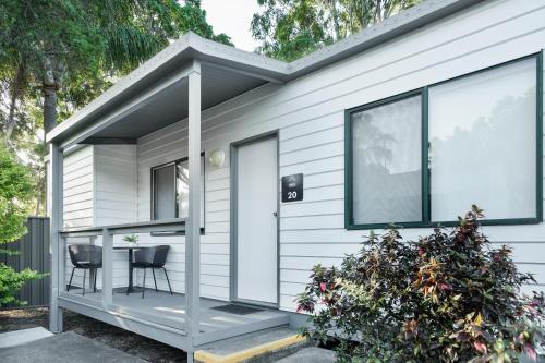 a tiny house with a porch and two chairs at Tasman Holiday Parks - Hervey Bay in Hervey Bay