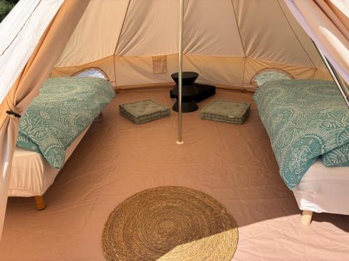 une tente avec 2 oreillers et un parasol dans l'établissement Tipi du lac, à Lacépède