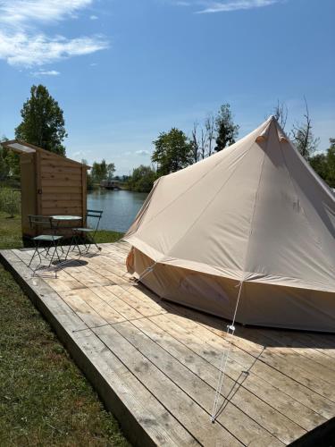 une tente sur une terrasse en bois à côté d'un lac dans l'établissement Tipi du lac, à Lacépède