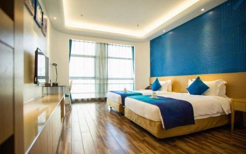 a bedroom with two beds and a blue wall at Beluga Sanya Discovery Ocean World in Shangsimacun