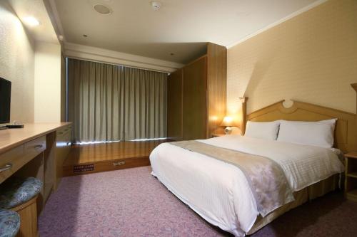 a hotel room with a large bed and a television at APVC Lukang Resort in Lugang