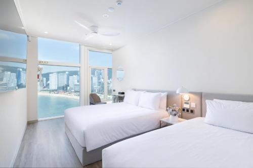 two beds in a hotel room with a large window at Ocean The Point Hotel Busan in Busan