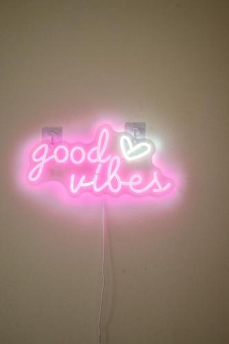 a neon sign that says good vibes on a wall at La Casa Goudacito in Gouda