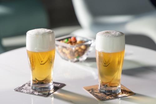 two glasses of beer on a table with a bowl of food at Ocean The Point Hotel Busan in Busan