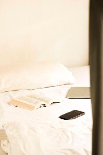 a book and a cell phone sitting on a bed at HOLY SHEET Hostel in Bangkok