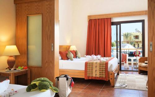 a hotel room with two beds and a balcony at Three Corners Fayrouz Plaza Beach Resort in Port Ghalib