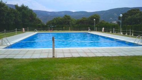 a large blue swimming pool with mountains in the background at Apartamentos Cañones de Guara y Formiga in Panzano