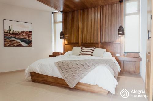 a bedroom with a large bed with a wooden headboard at 103 Arje Suites Campestre by Alegría Housing in Las Pilas